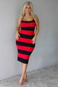A woman wearing a red and black striped body-con midi dress standing indoors against a white wall with white marble flooring. 