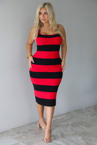A woman wearing a red and black striped body-con midi dress standing indoors against a white wall with white marble flooring. 