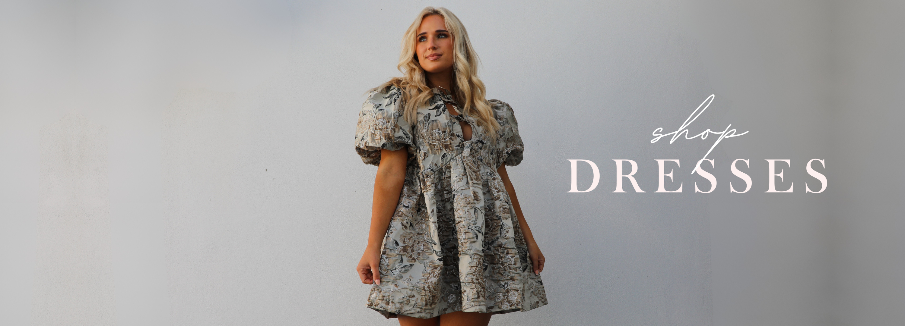 Woman wearing a floral dress with 'shop dresses' text on a gray background