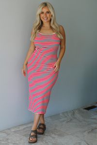 Woman in a red and white striped dress standing indoors against a white wall with white marble flooring. 