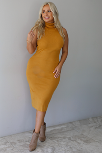 A woman wearing a marigold sleeveless midi dress with a high, turtle neckline, ribbed textured material, and is fitted, standing indoors against a white wall with white marble flooring. 
