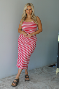 Woman in a red and white striped dress standing indoors against a white wall with white marble flooring. 