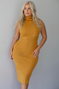 A woman wearing a marigold sleeveless midi dress with a high, turtle neckline, ribbed textured material, and is fitted, standing indoors against a white wall.