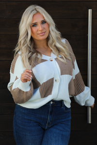 Close up of a woman model wearing a white and tan checkered patterned cardigan and dark wash denim. The cardigan has functional button closures in the front, is lightweight, and has a relaxed fit. 