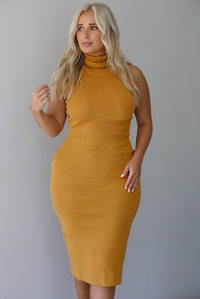 A woman wearing a marigold sleeveless midi dress with a high, turtle neckline, ribbed textured material, and is fitted, standing indoors against a white wall.